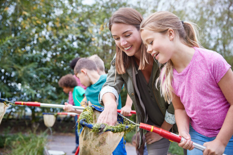 Jugendleiterin erkundet mit Kindern die Natur