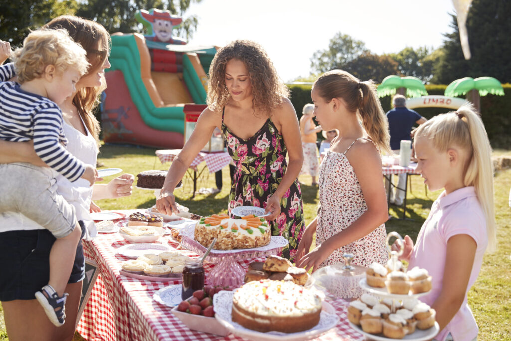 Familien und Kinder am Kuchenstand auf einem Sommerfest im Grünen