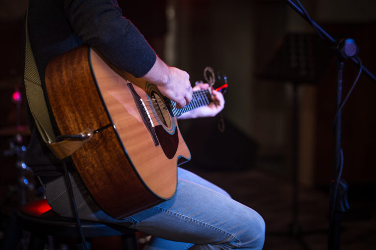 Musiker spielt Akustikgitarre auf einer kleinen Bühne